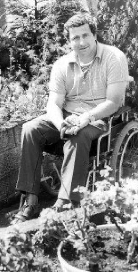 Black and white photo of Dave Purdy in his garden sitting in his wheelchair